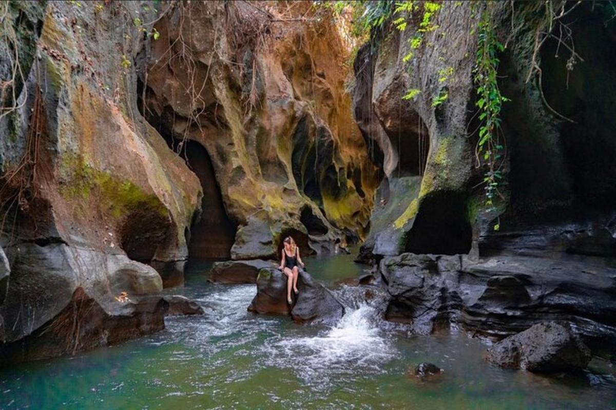 una mujer sentada en una roca en un estanque de agua