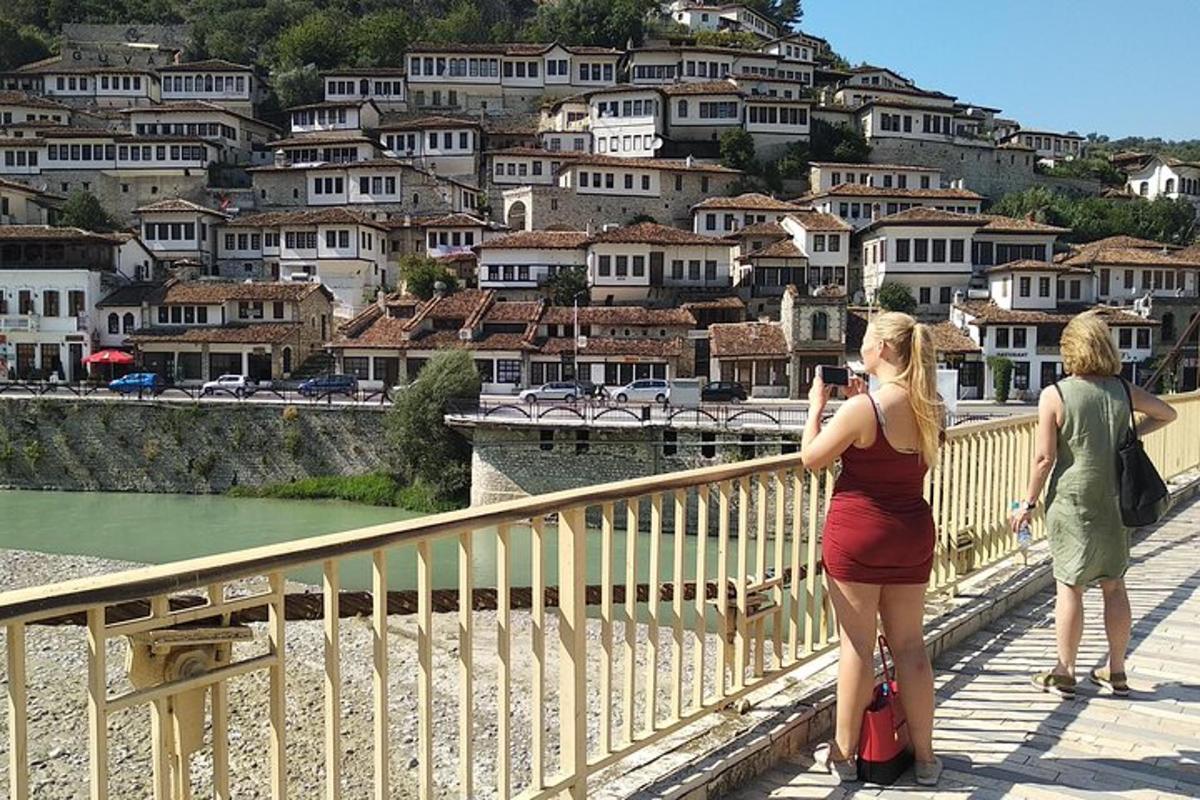 Δύο γυναίκες στέκονται σε μια γέφυρα και φωτογραφίζουν μια πόλη