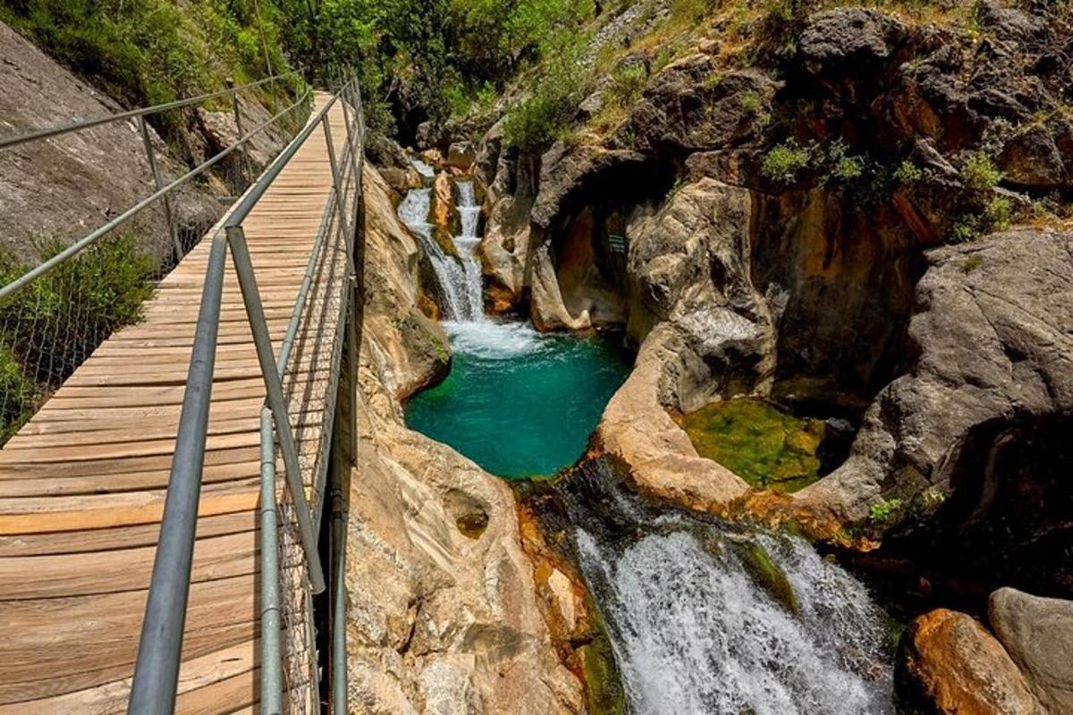 uma ponte de madeira sobre um rio com uma cachoeira