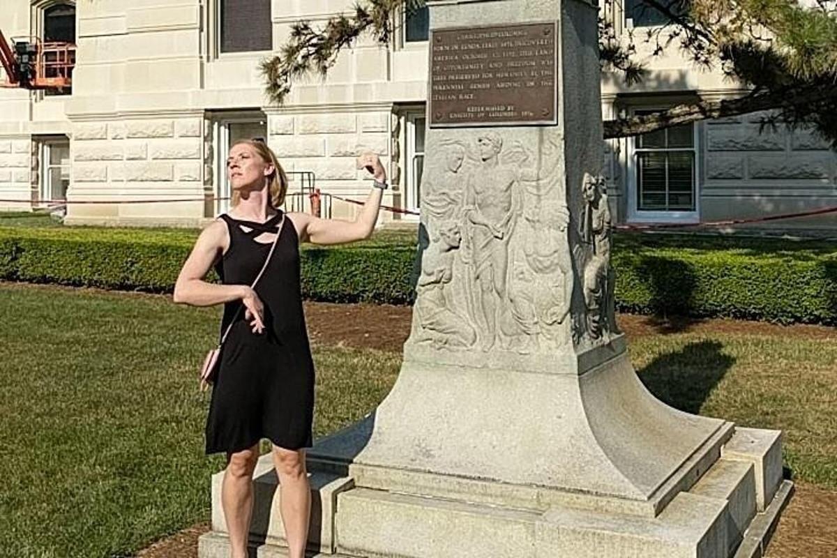 seorang wanita berpakaian hitam berdiri di sebelah monumen