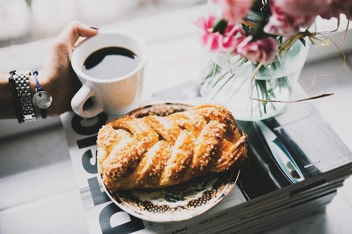 một người cầm một tách cà phê và một đĩa thức ăn