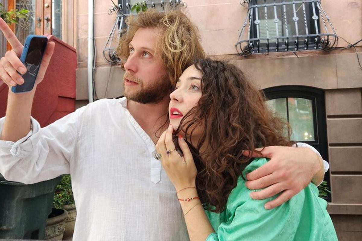 um homem e uma mulher tirando uma foto com um celular