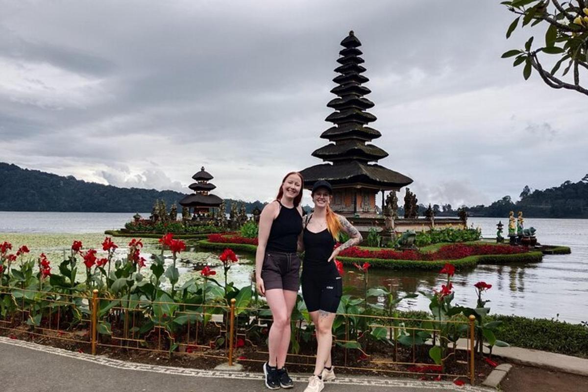 duas mulheres em pé em frente a um jardim com um lago