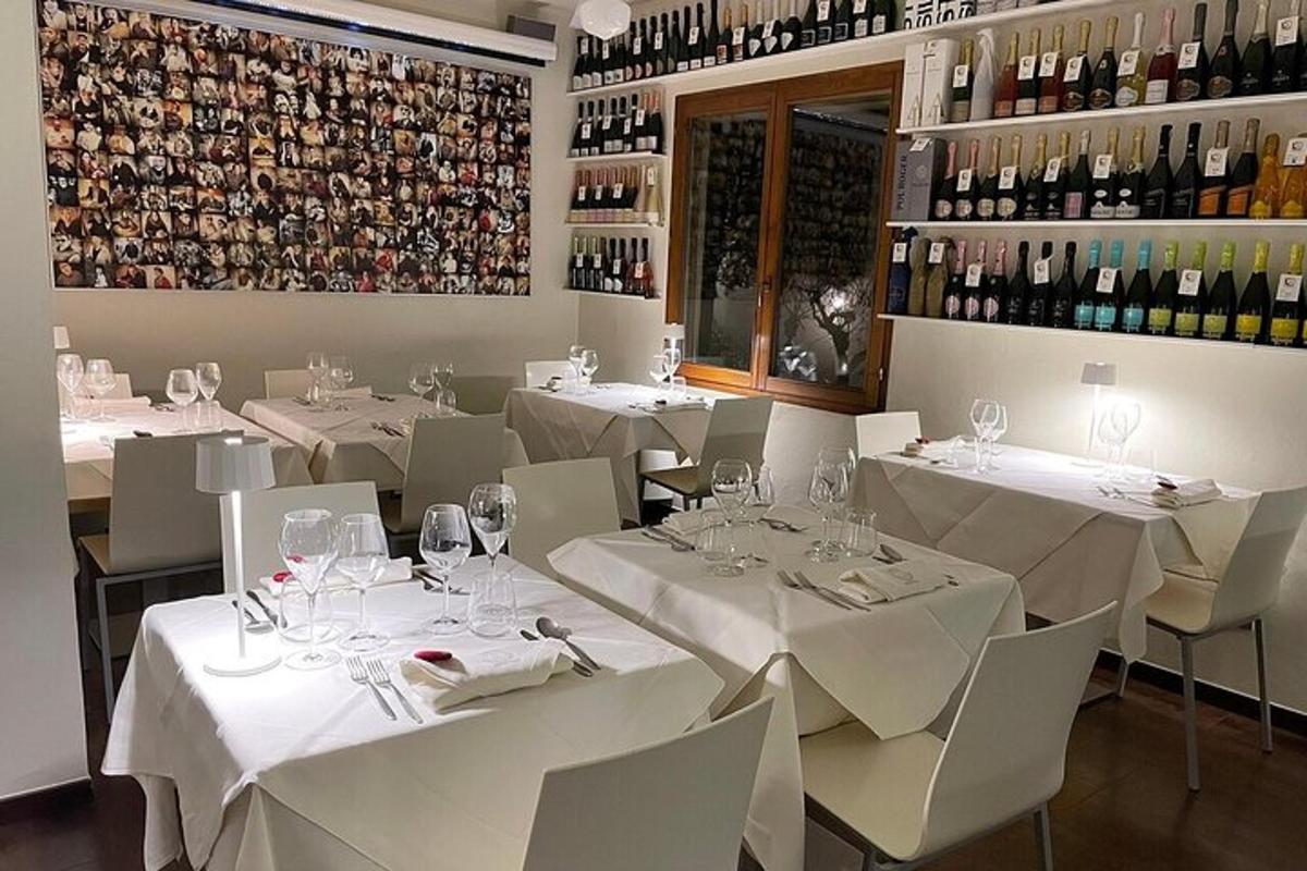 Un restaurante con mesas y sillas blancas y botellas de vino.