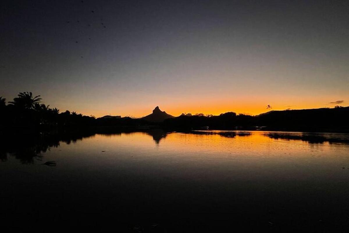 um pôr do sol sobre um lago com uma montanha ao fundo