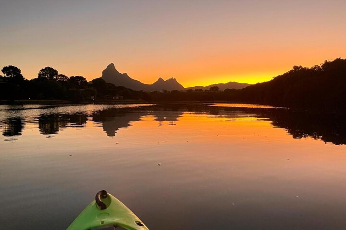 um caiaque em um rio com o pôr do sol ao fundo