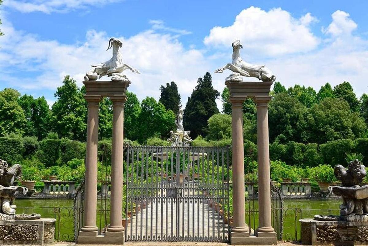 a gate in a garden with statues on top of it