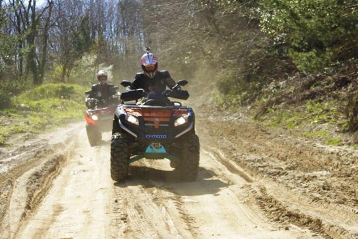 to personer kører på ATV'er på en grusvej