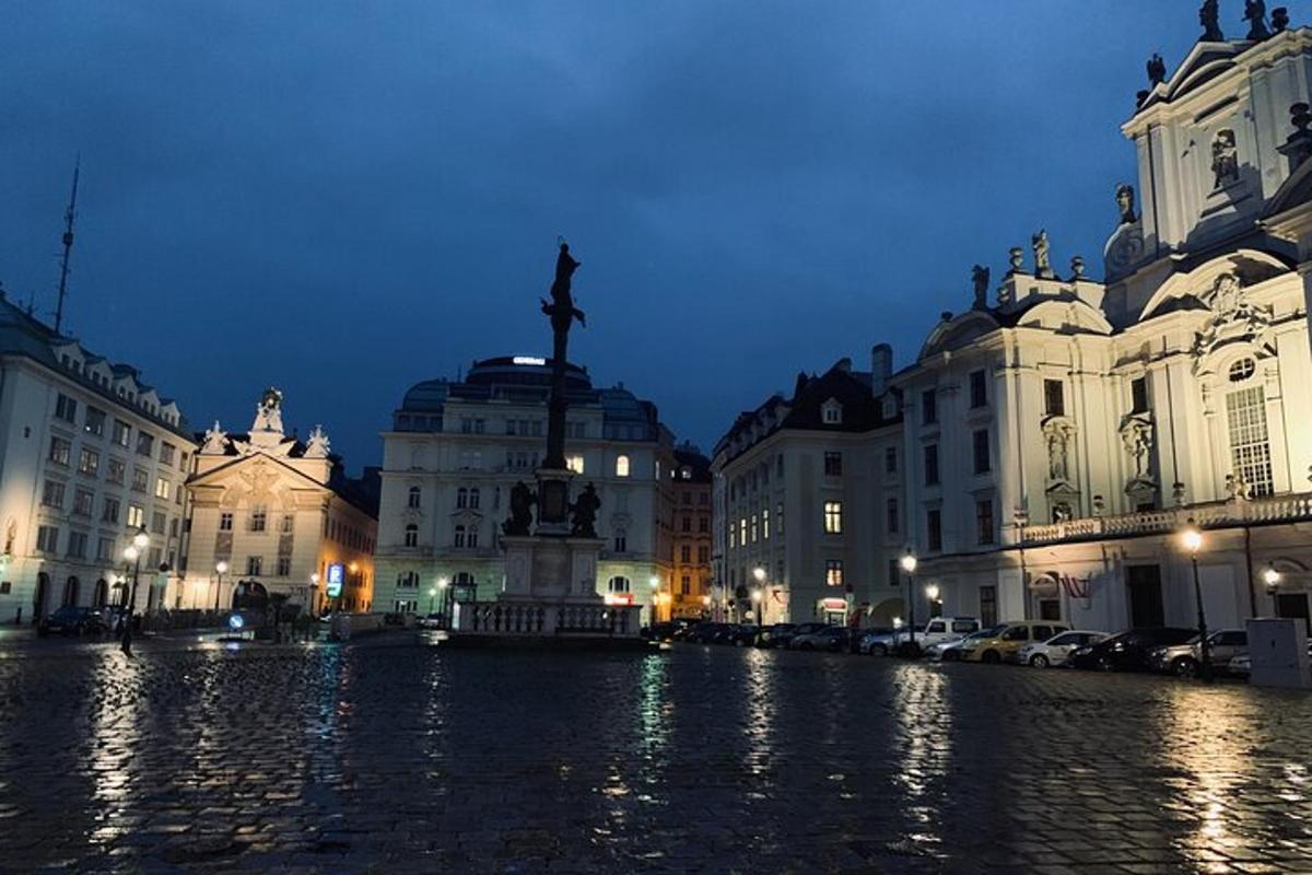 Una calle de la ciudad con edificios y una estatua por la noche.