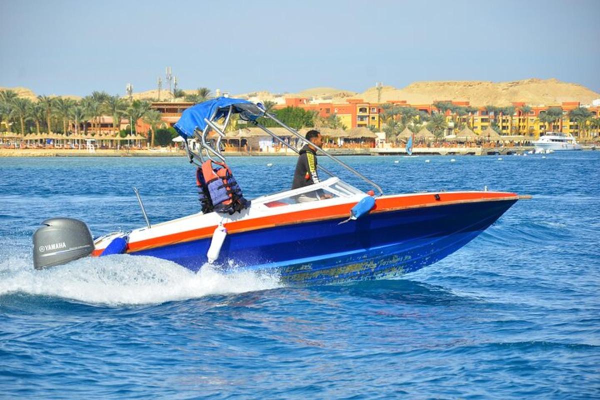 một người đàn ông trên chiếc thuyền màu xanh và cam trên mặt nước
