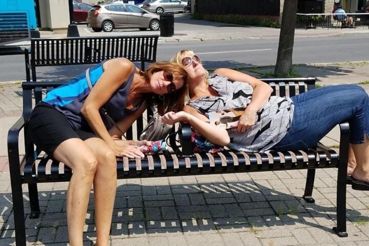 dvě ženy leží na lavičce v parku