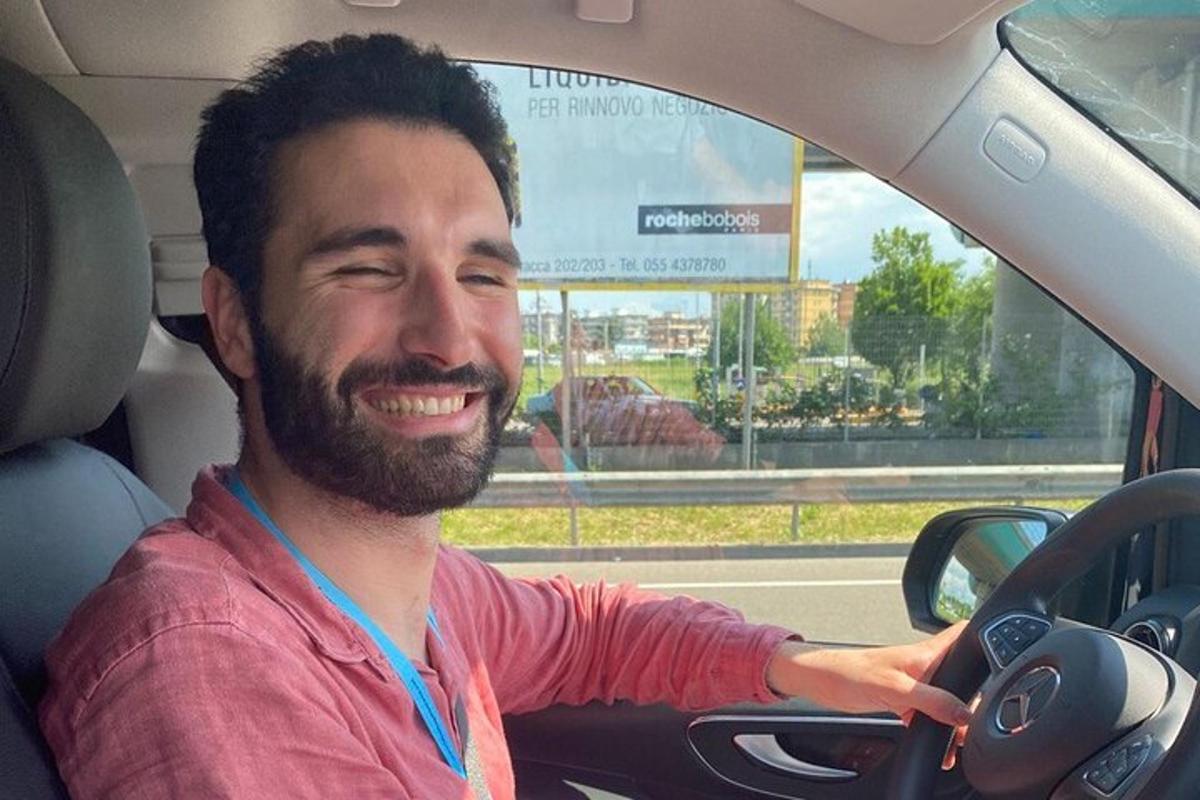 Un hombre sonríe mientras conduce un coche.