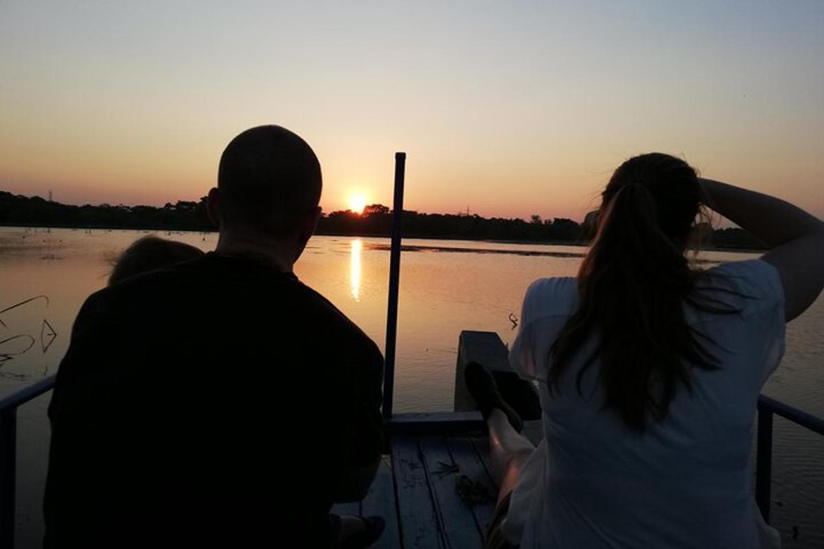 Una pareja sentada en un barco mirando la puesta de sol