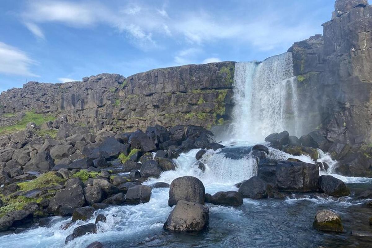 een waterval aan de zijkant van een berg met rotsen