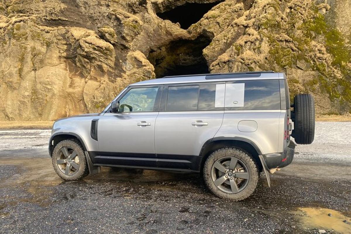 một chiếc xe jeep màu trắng đậu trước một hang động