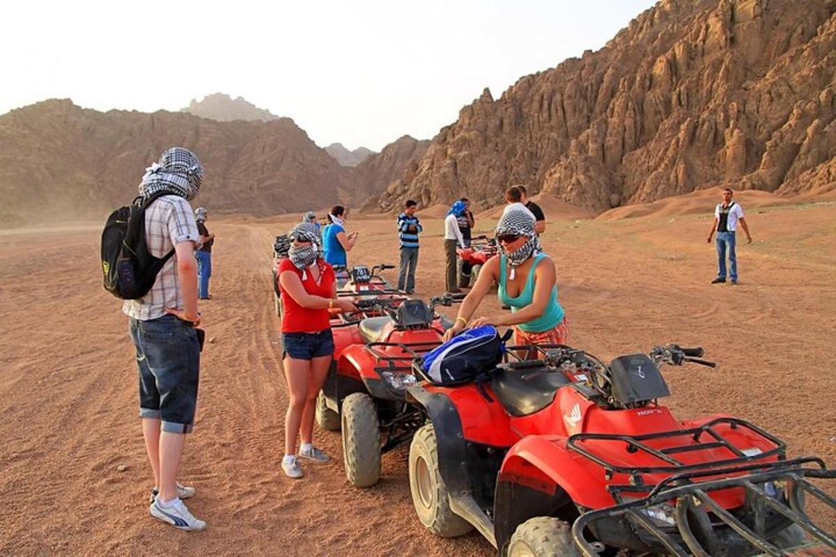un gruppo di persone in piedi attorno ai quad nel deserto