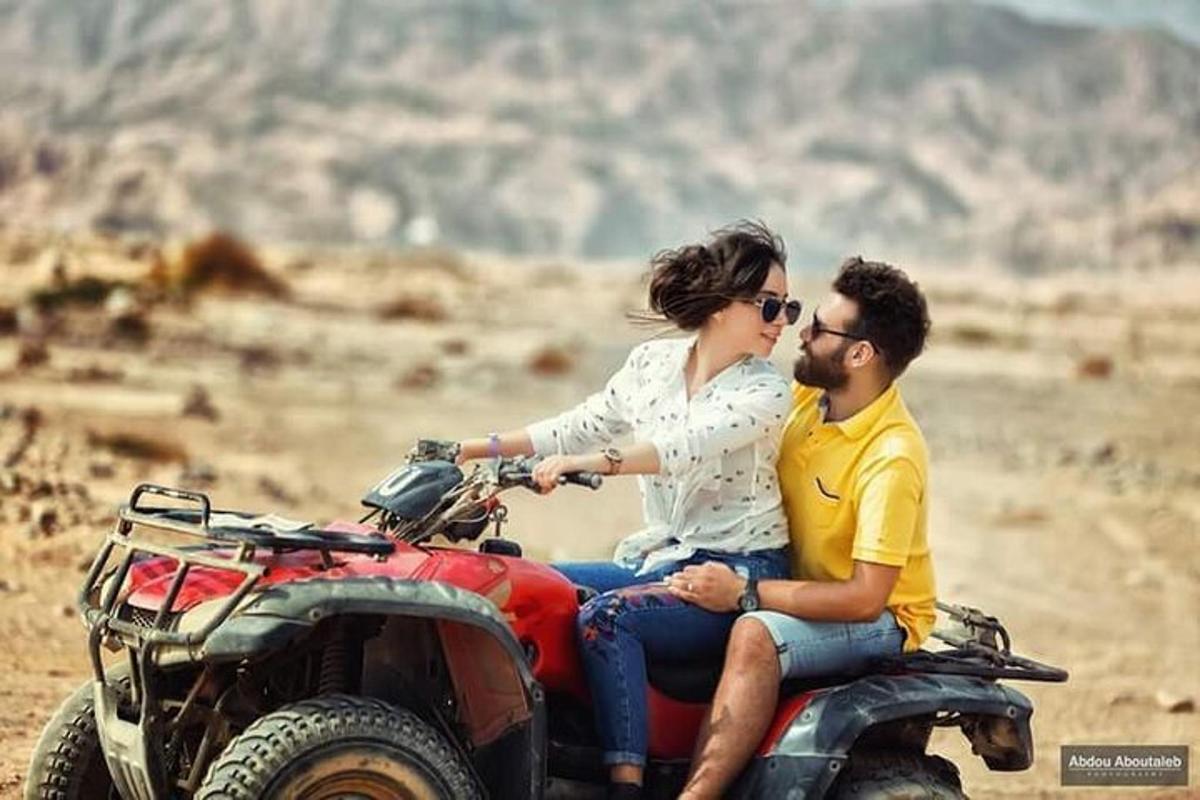 un home i una dona asseguts en un quad al desert