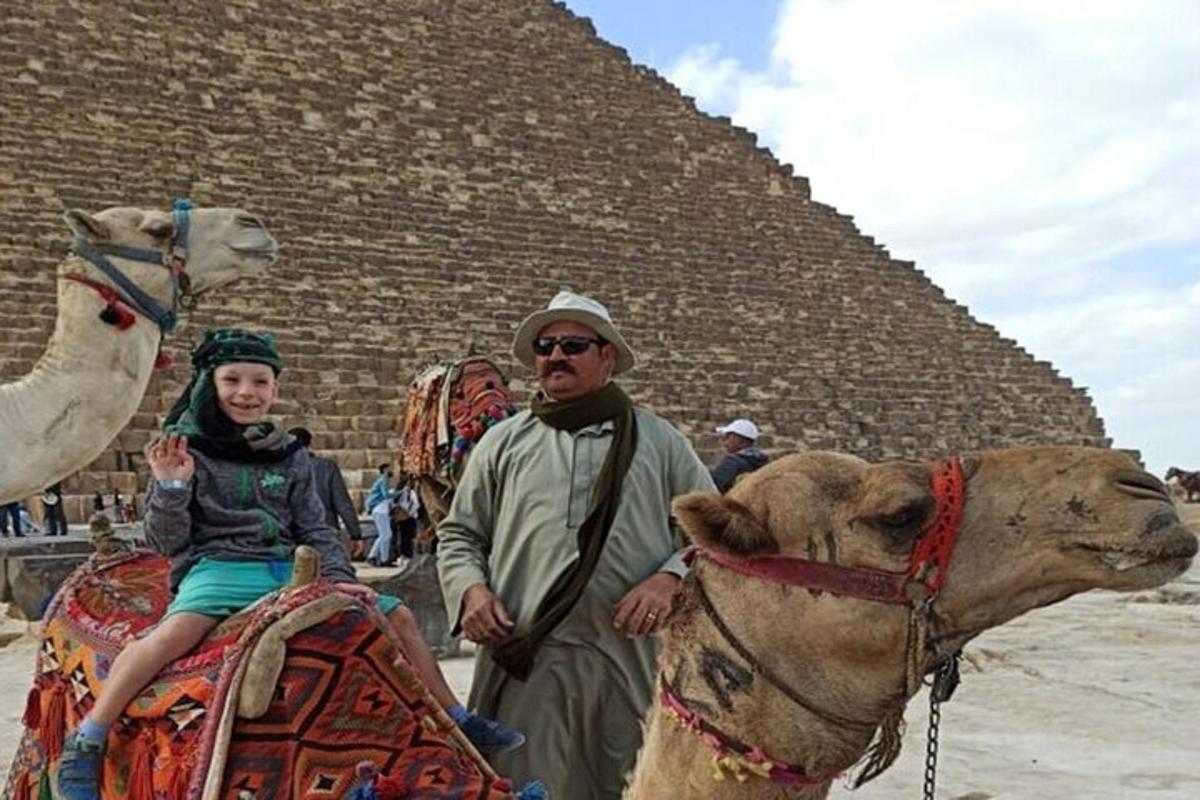muž a dievča sediaci na ťave pred pyramídou