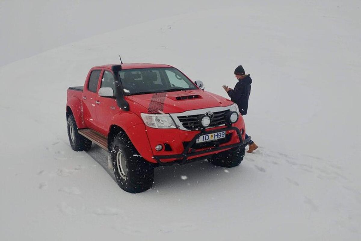 mees seisab lumes punase veoauto kõrval