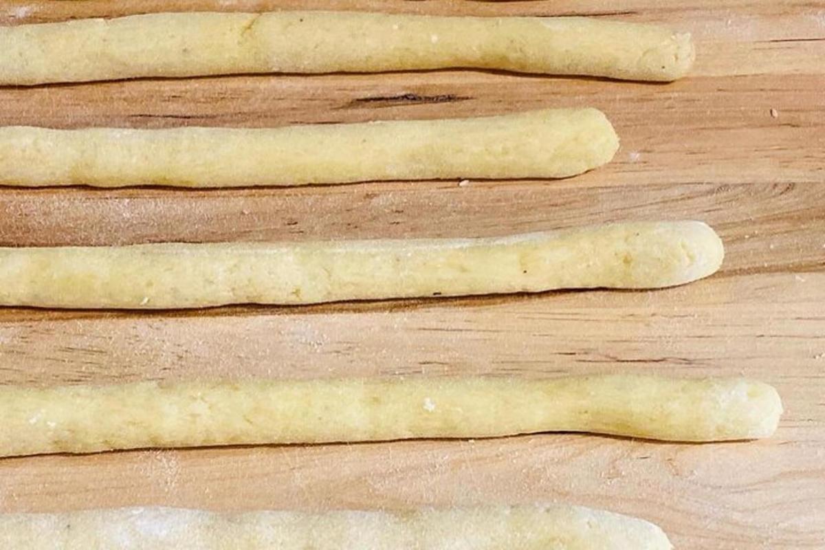 quatre bastonets de pa crus asseguts sobre una taula de fusta