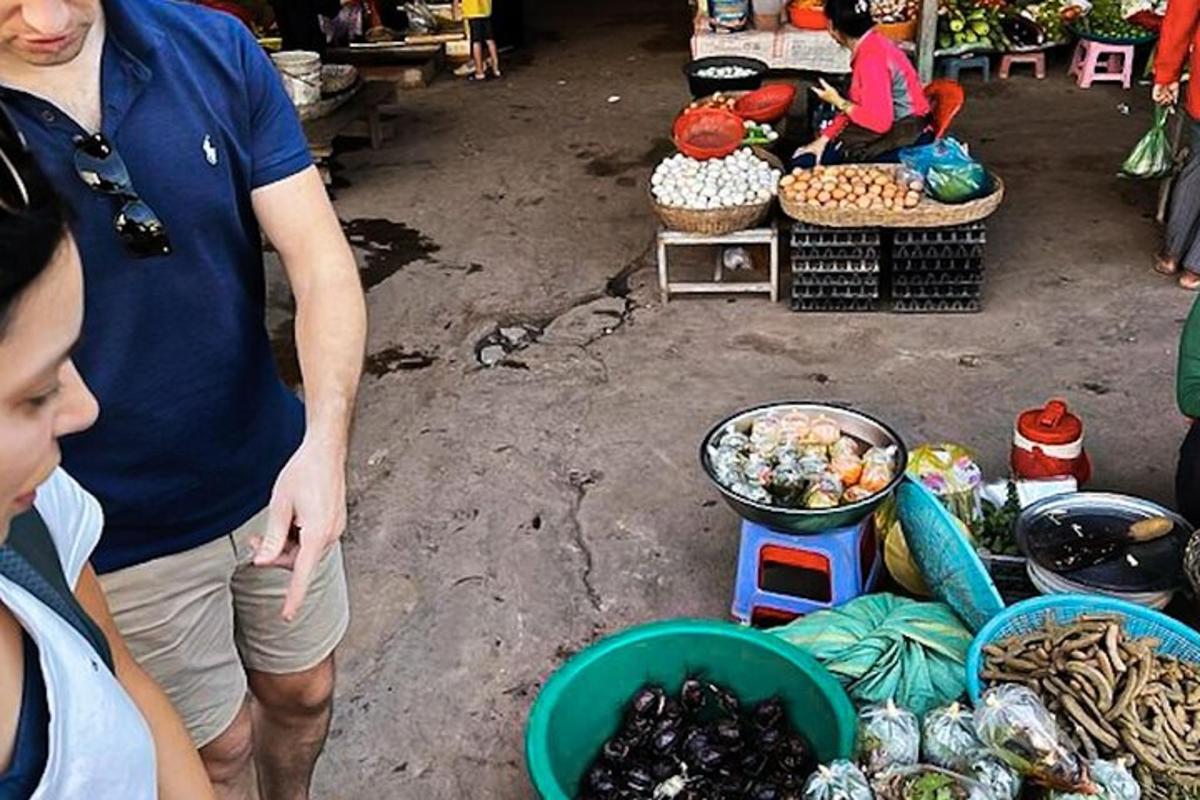 muž stojící na trhu s hromadou jídla