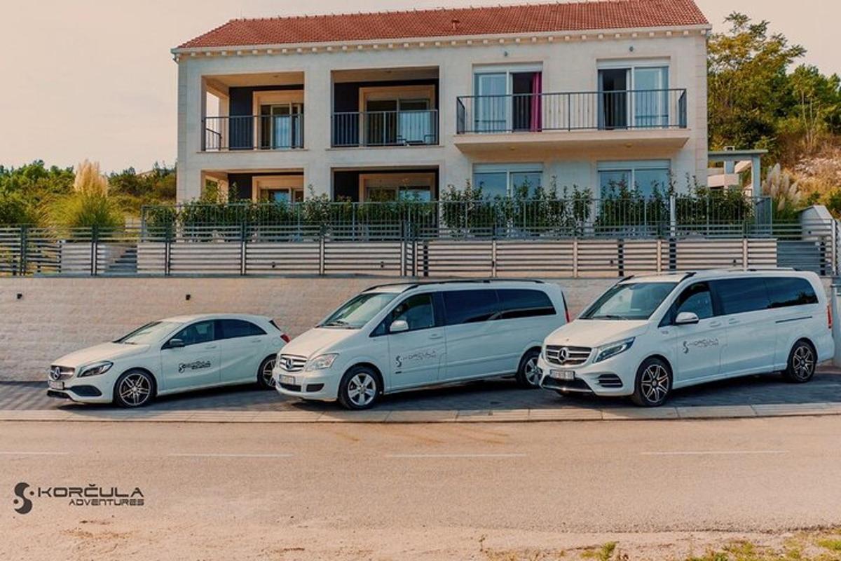 tři auta zaparkovaná na parkovišti před domem