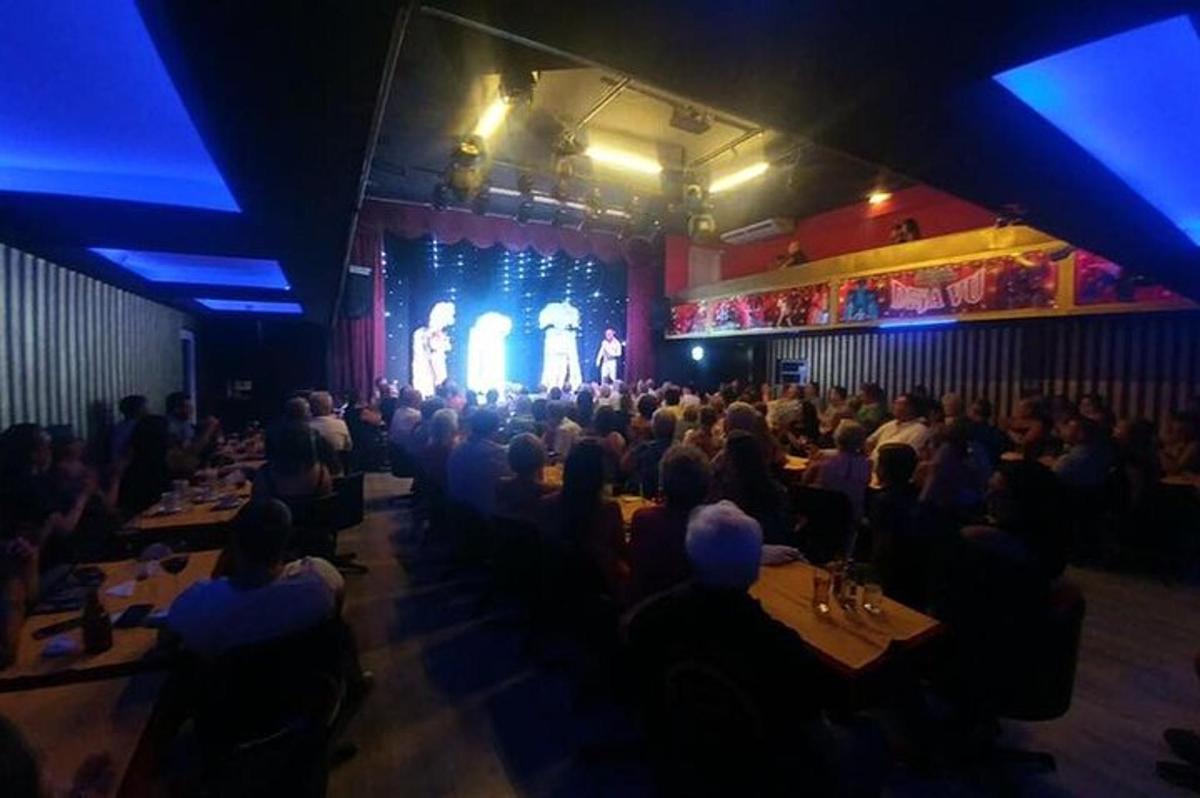 una folla di persone sedute ai tavoli di un teatro