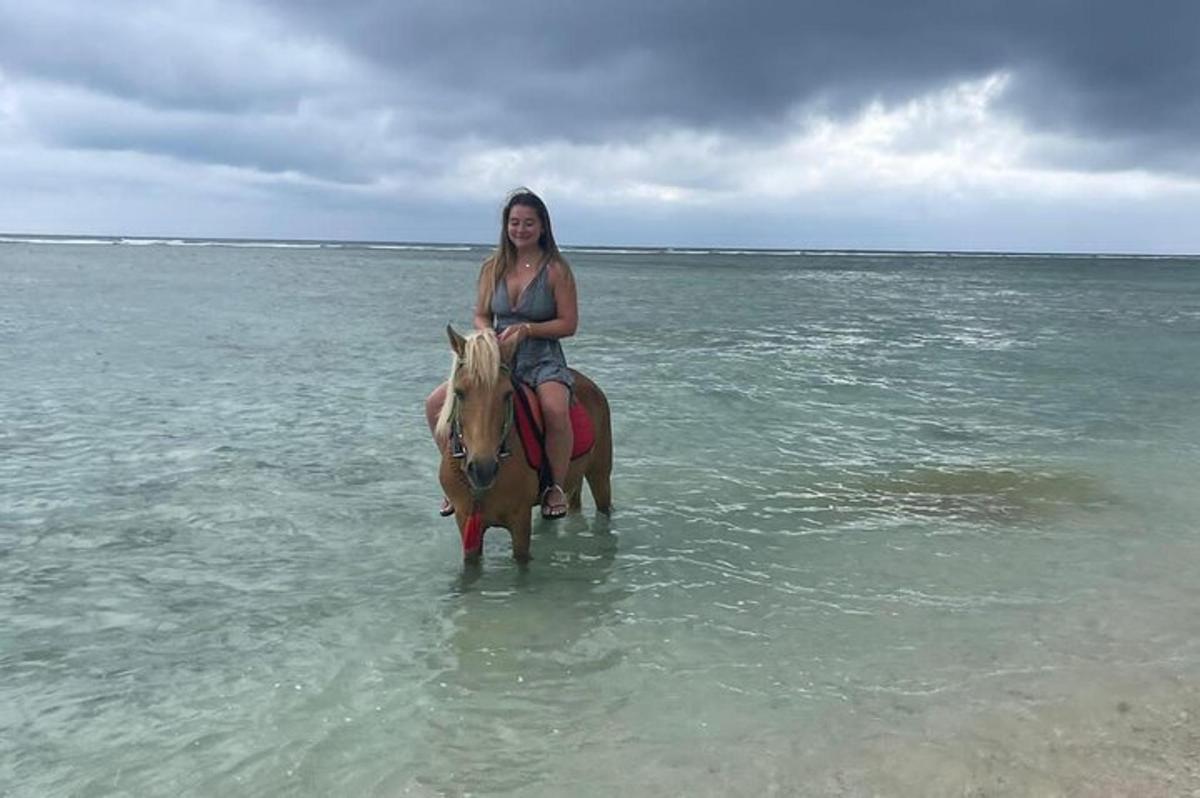 a woman riding a horse in the ocean