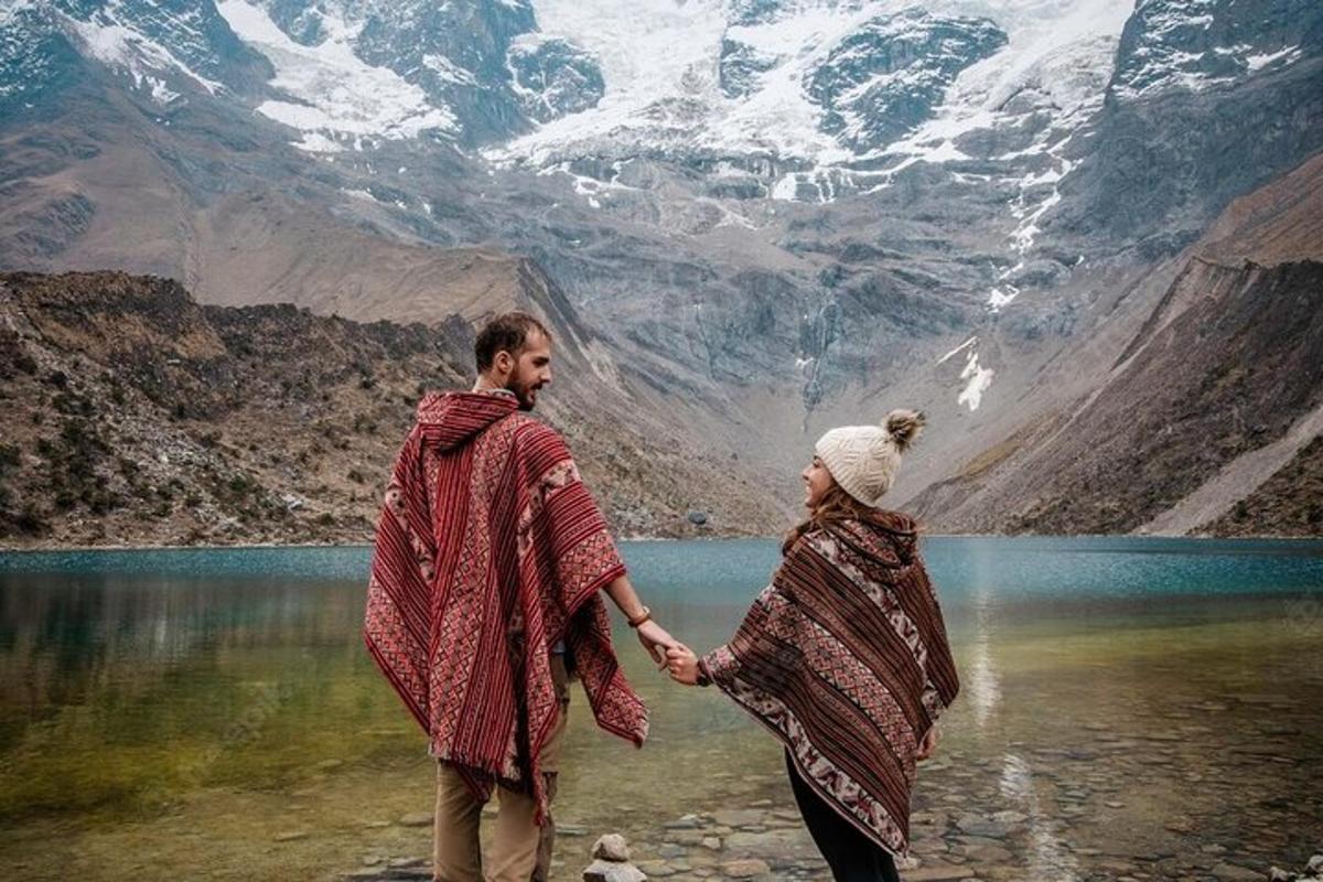 un uomo e una donna che si tengono per mano mentre sono in piedi di fronte a una montagna