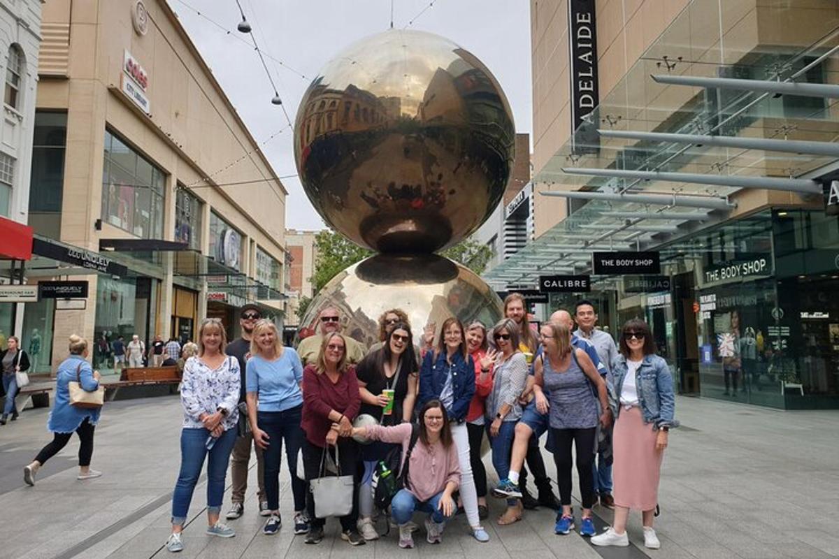 en gruppe mennesker poserer til et billede foran en skulptur