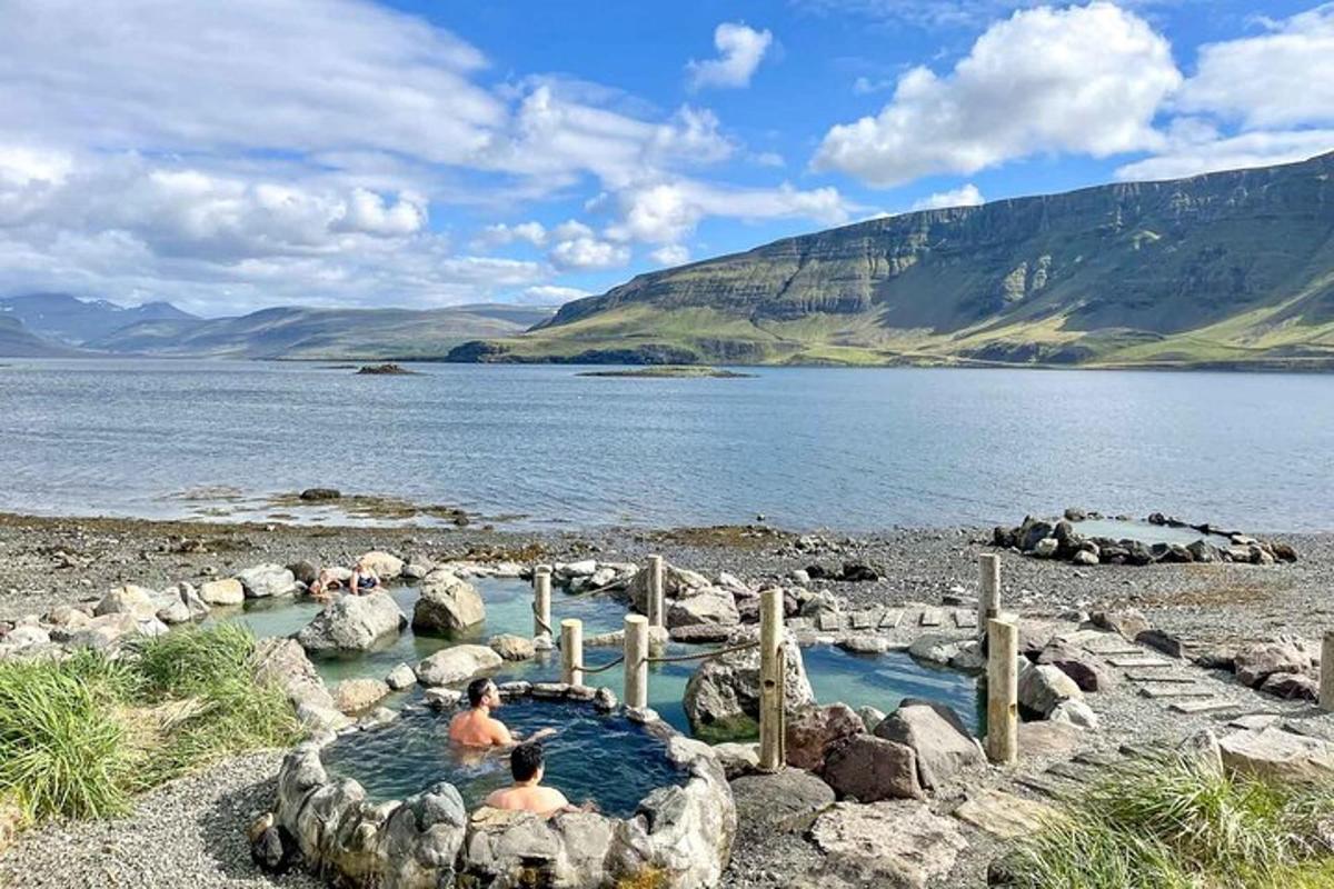 two people sitting in a hot tub next to a body of water