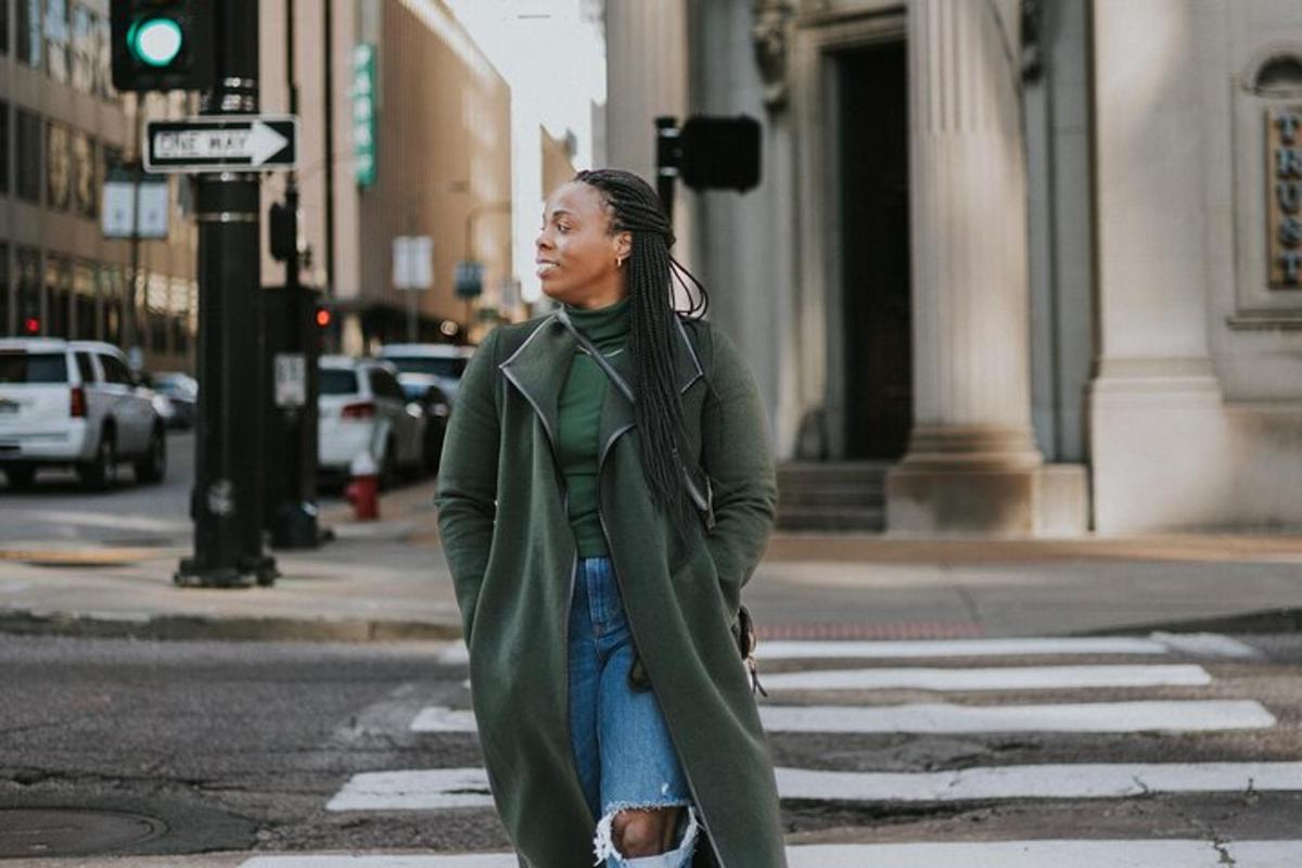 a woman in a green coat crossing a street