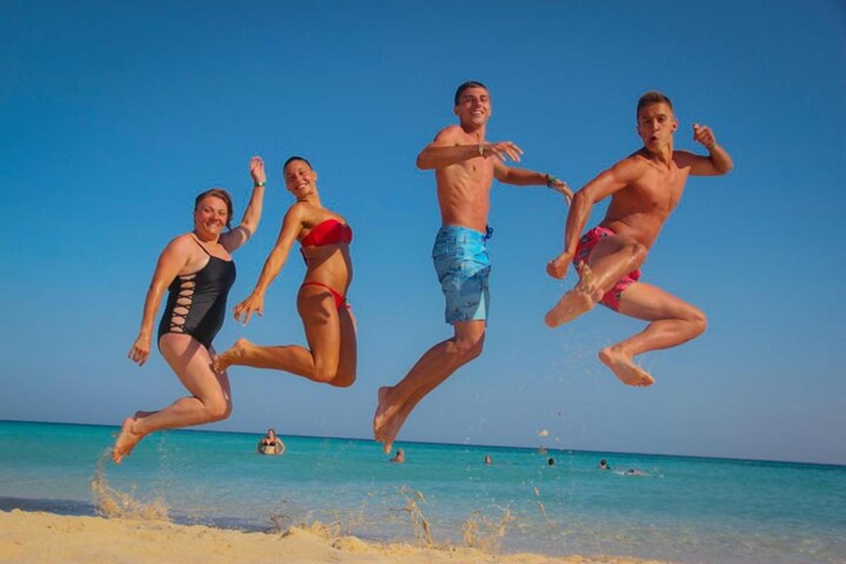 skupina ljudi, ki skačejo v zrak na plaži