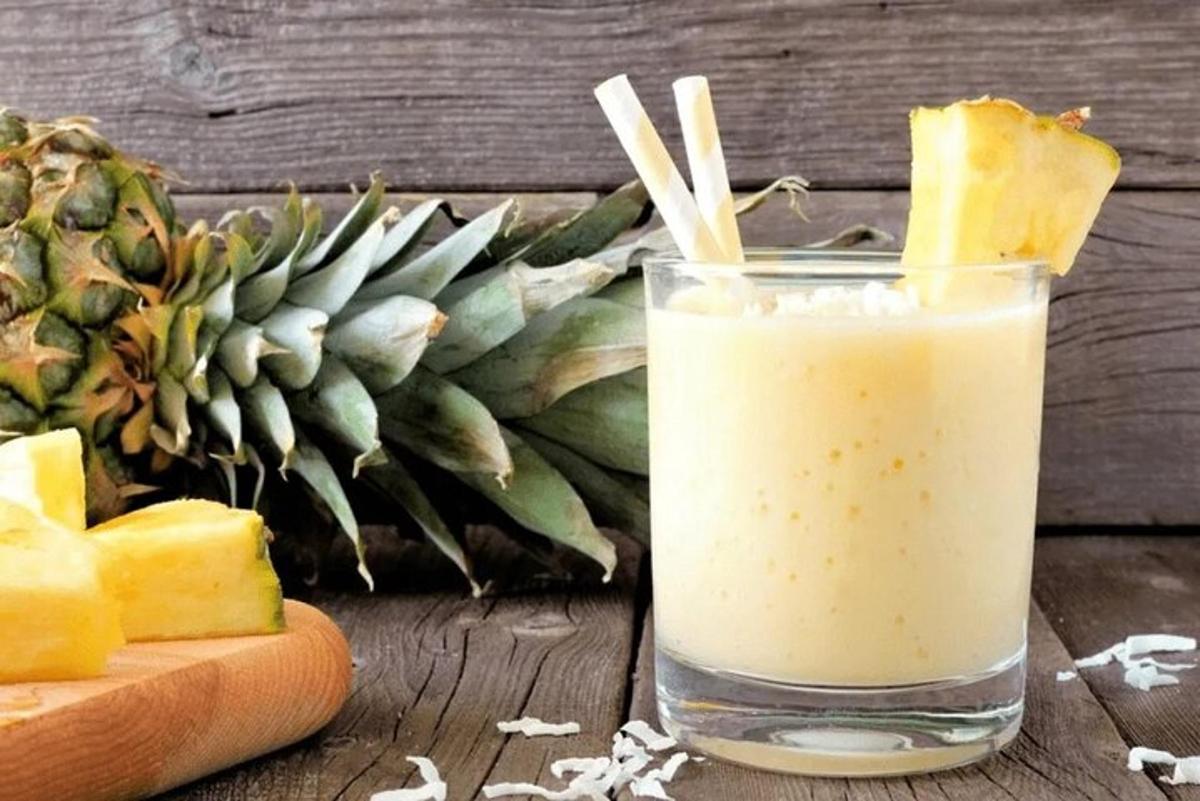 a drink in a glass next to a pineapple