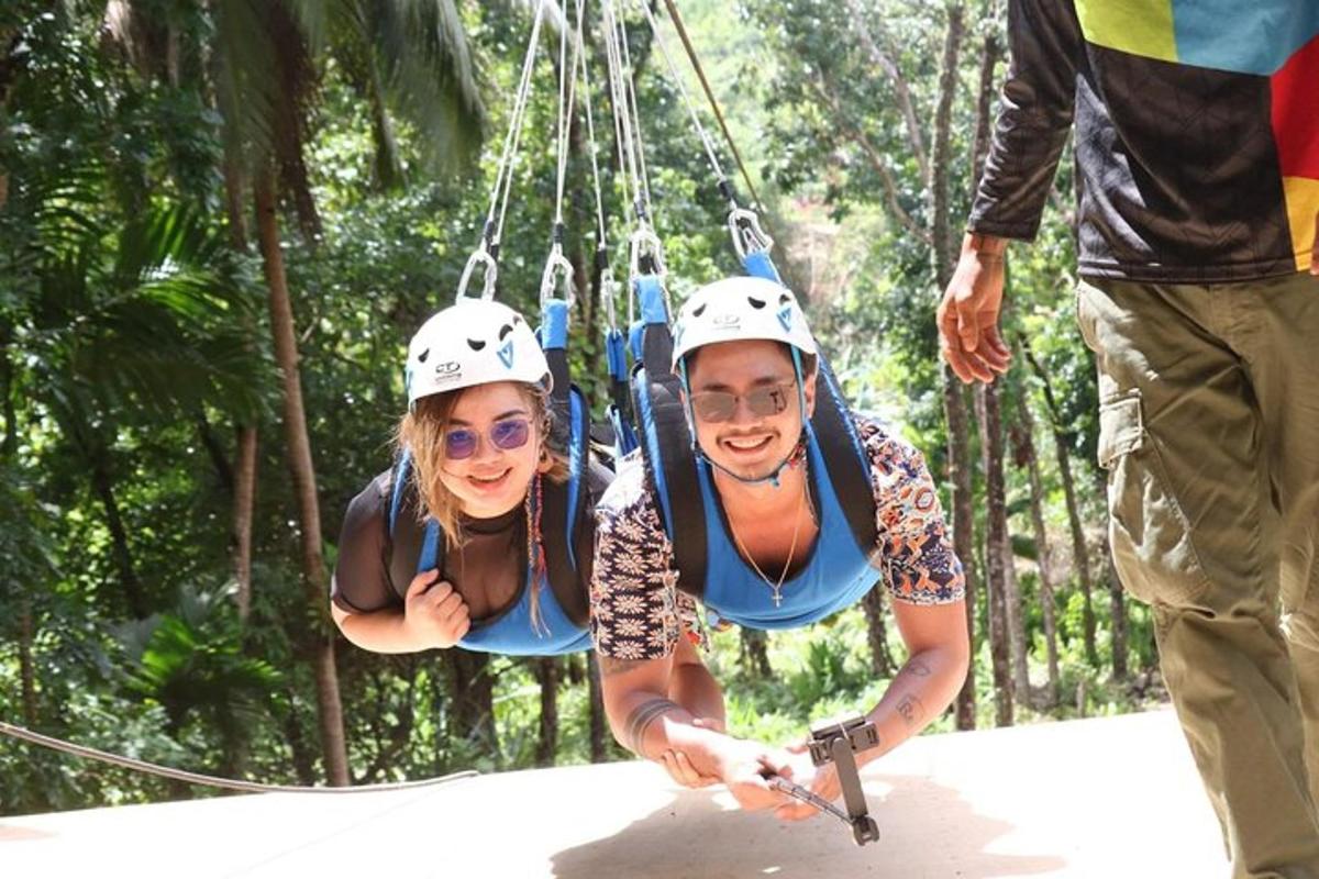 a man and woman on a zip line in the jungle