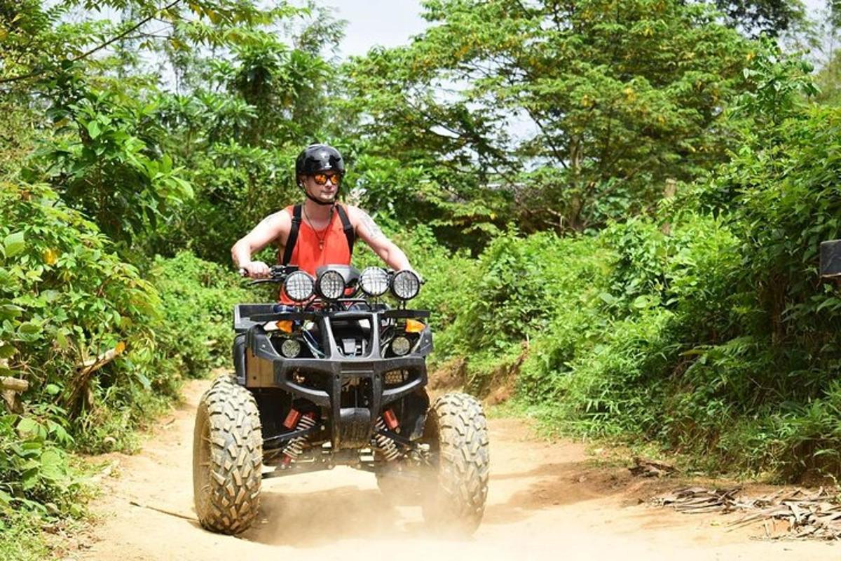 a man riding a four wheeler on a dirt trail