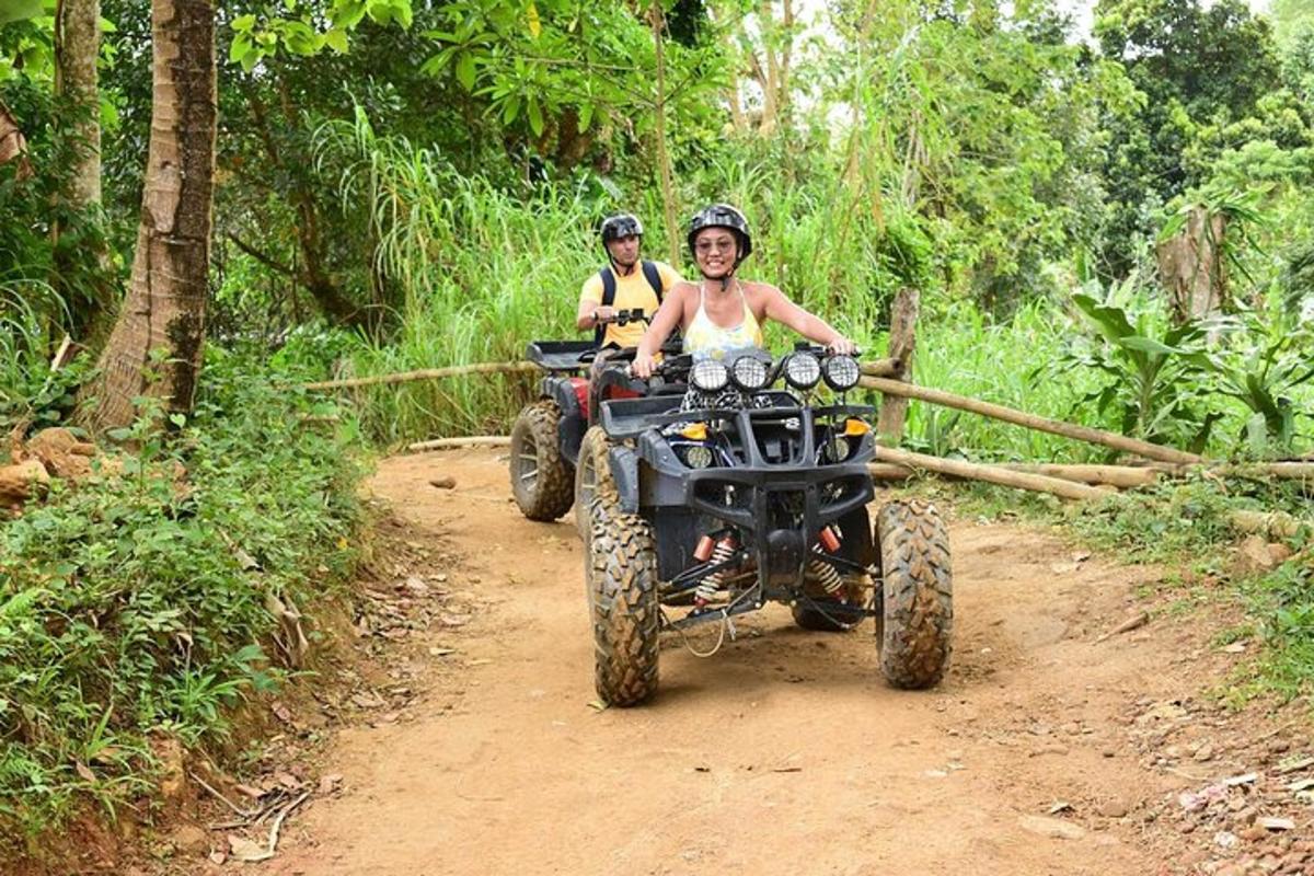 a man and a woman riding on a four wheeler on a dirt trail