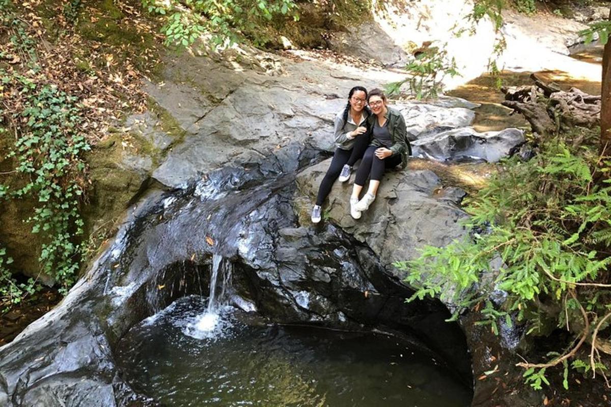 Dos mujeres sentadas en una roca cerca de una cascada