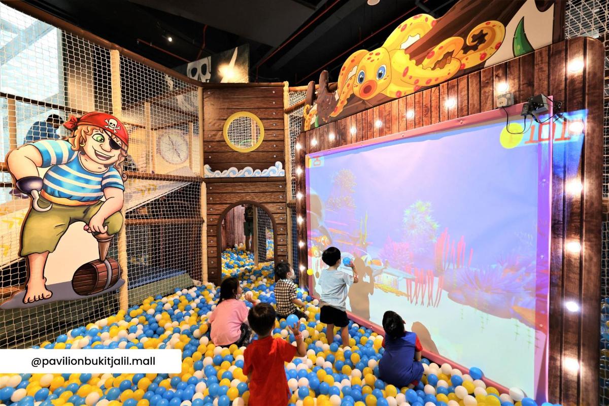 a group of children are sitting in a room with a stage