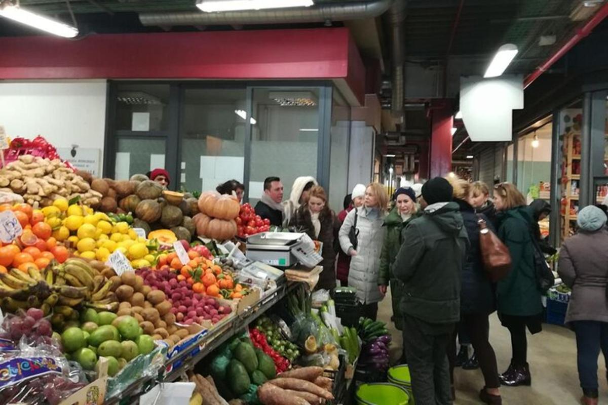 egy csoport ember álldogál egy gyümölcspiac körül