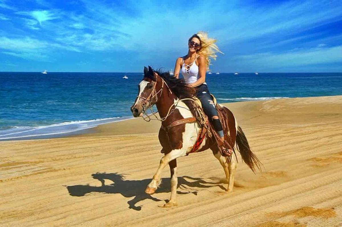 una mujer montando a caballo en la playa