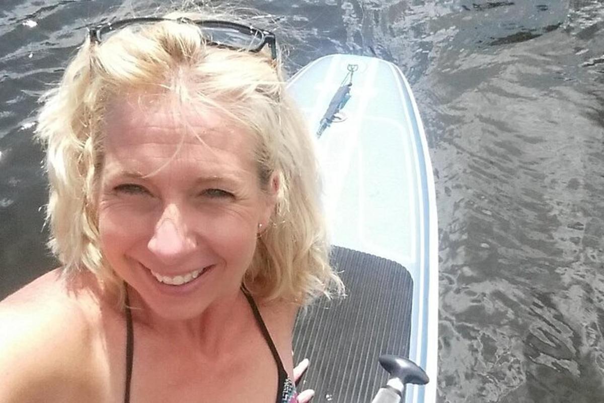 a woman sitting on a board in the water next to a surfboard