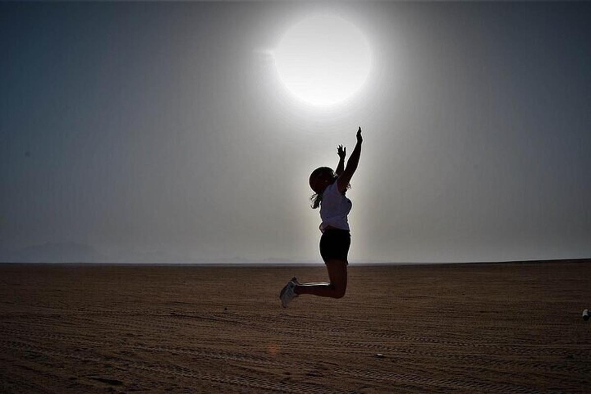 una mujer saltando en medio del desierto