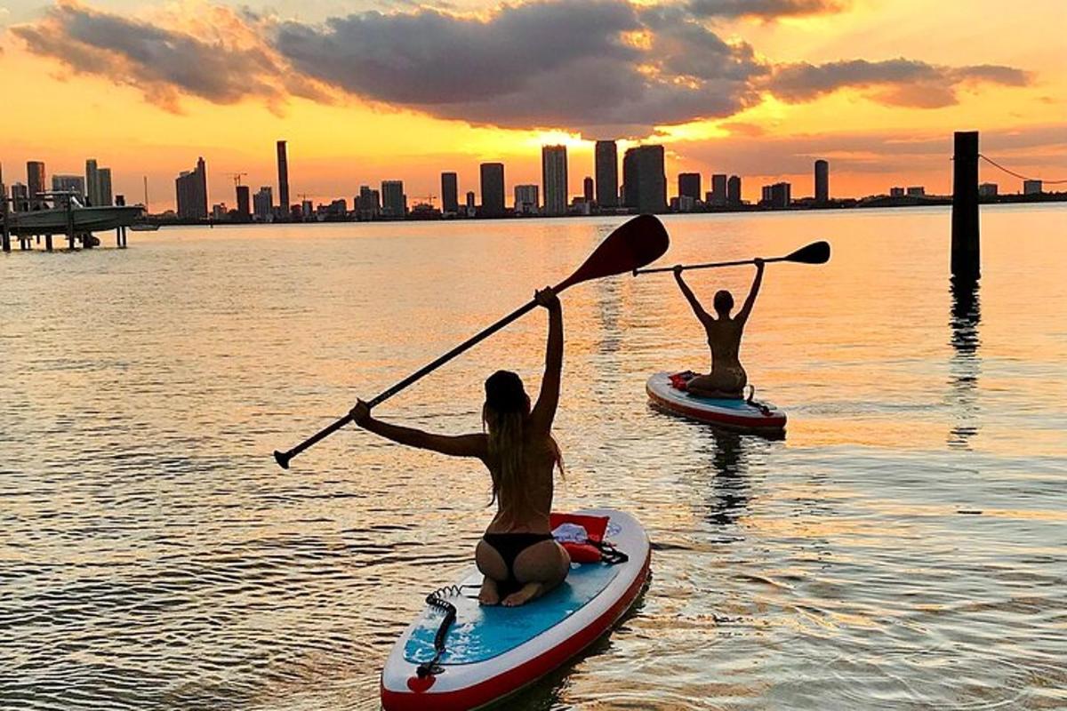 due persone su tavole da paddle in acqua con la città