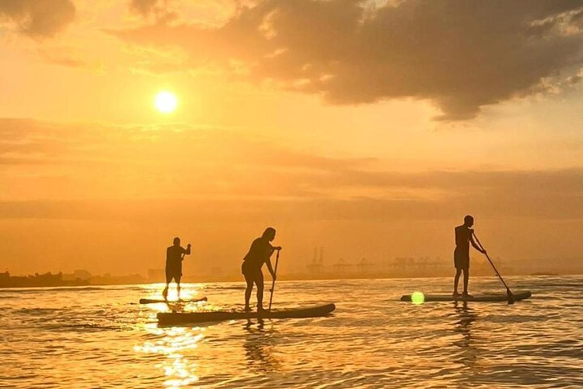 tre persone su tavole da paddle in acqua al tramonto
