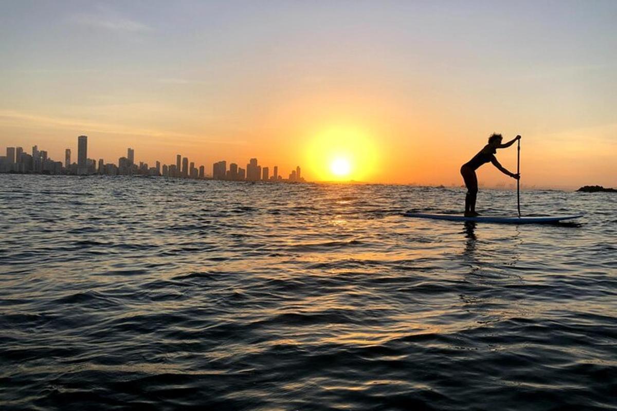 una persona su una tavola da paddle in acqua al tramonto