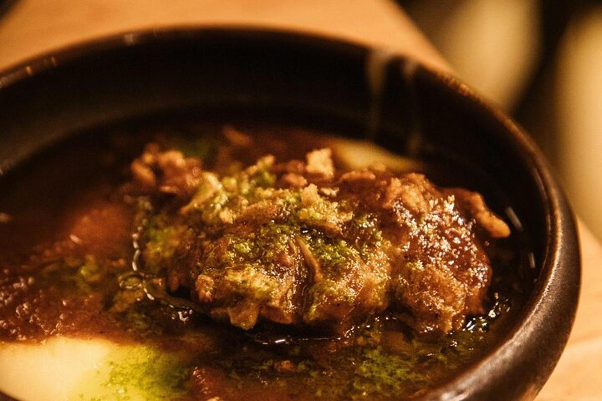 ένα μαύρο μπολ με φαγητό με κρέας και σάλτσα
