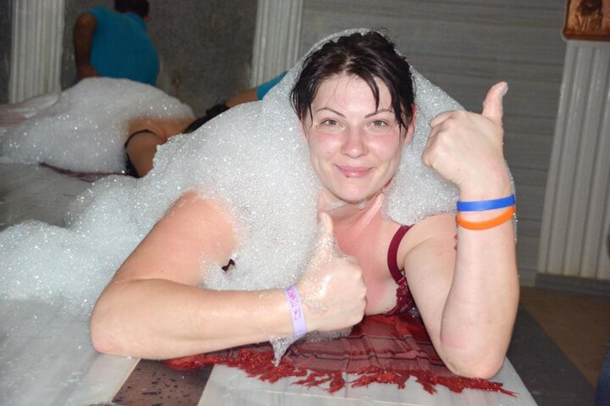 žena sedící ve vaně pokrytá bublinami