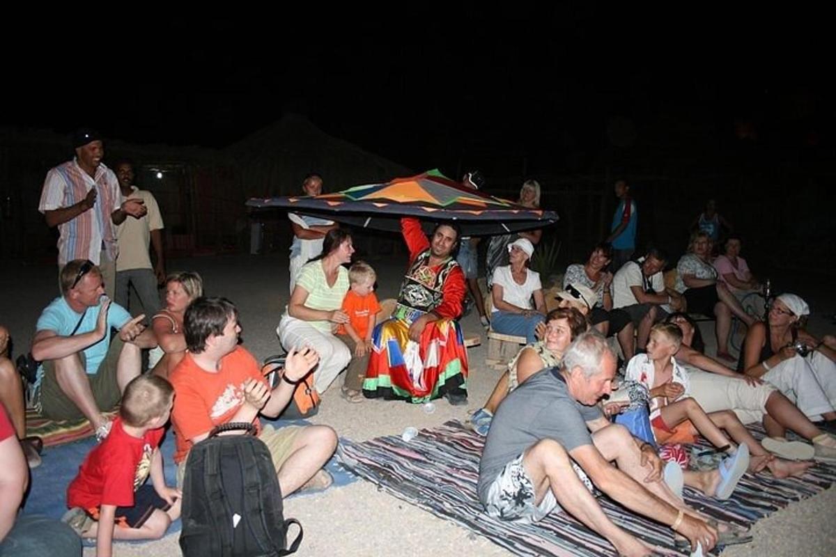 sekumpulan orang yang duduk di pantai pada waktu malam