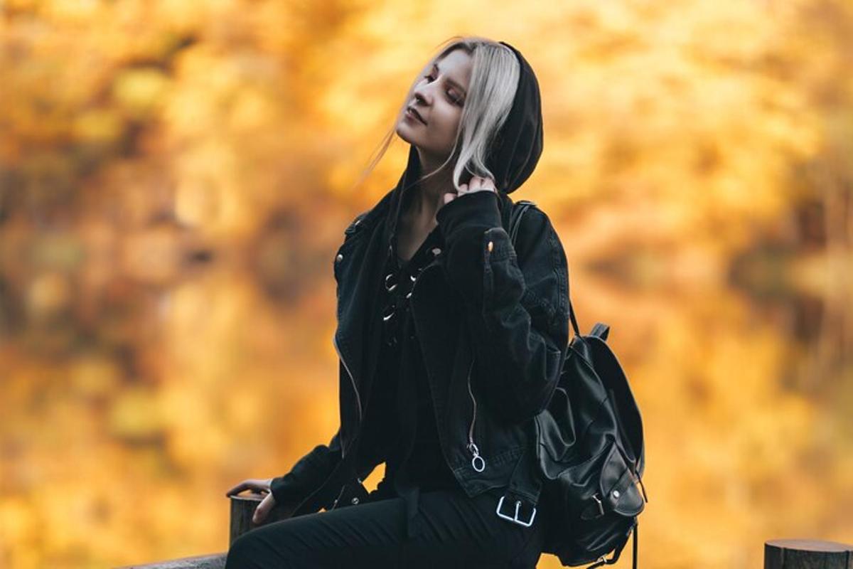 жінка в чорній куртці сидить на стіні